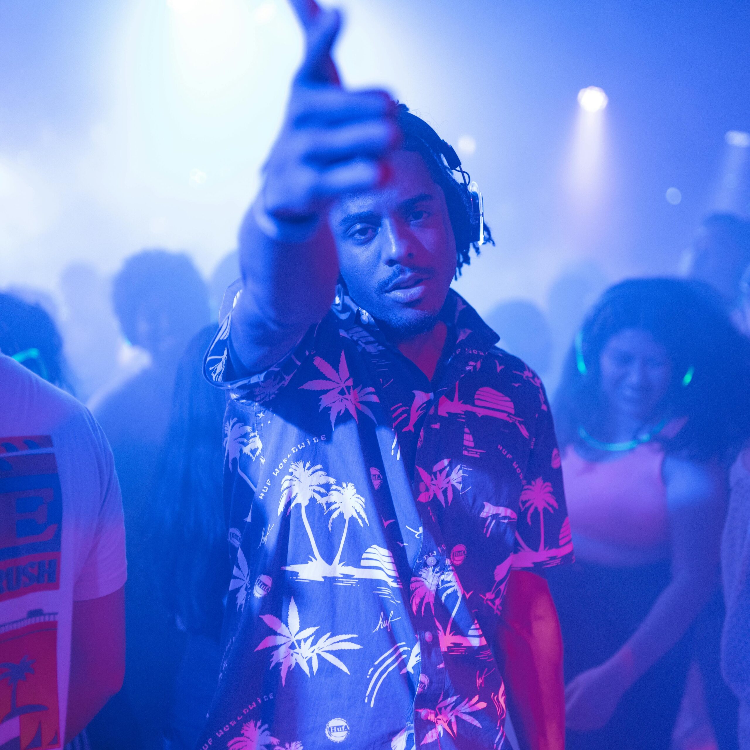 Vibrant nightclub scene with a lively partygoer and dancing crowd under colorful lights.